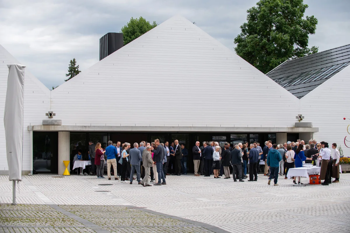 Mehrere Menschen stehen zusammen und reden und lachen. 